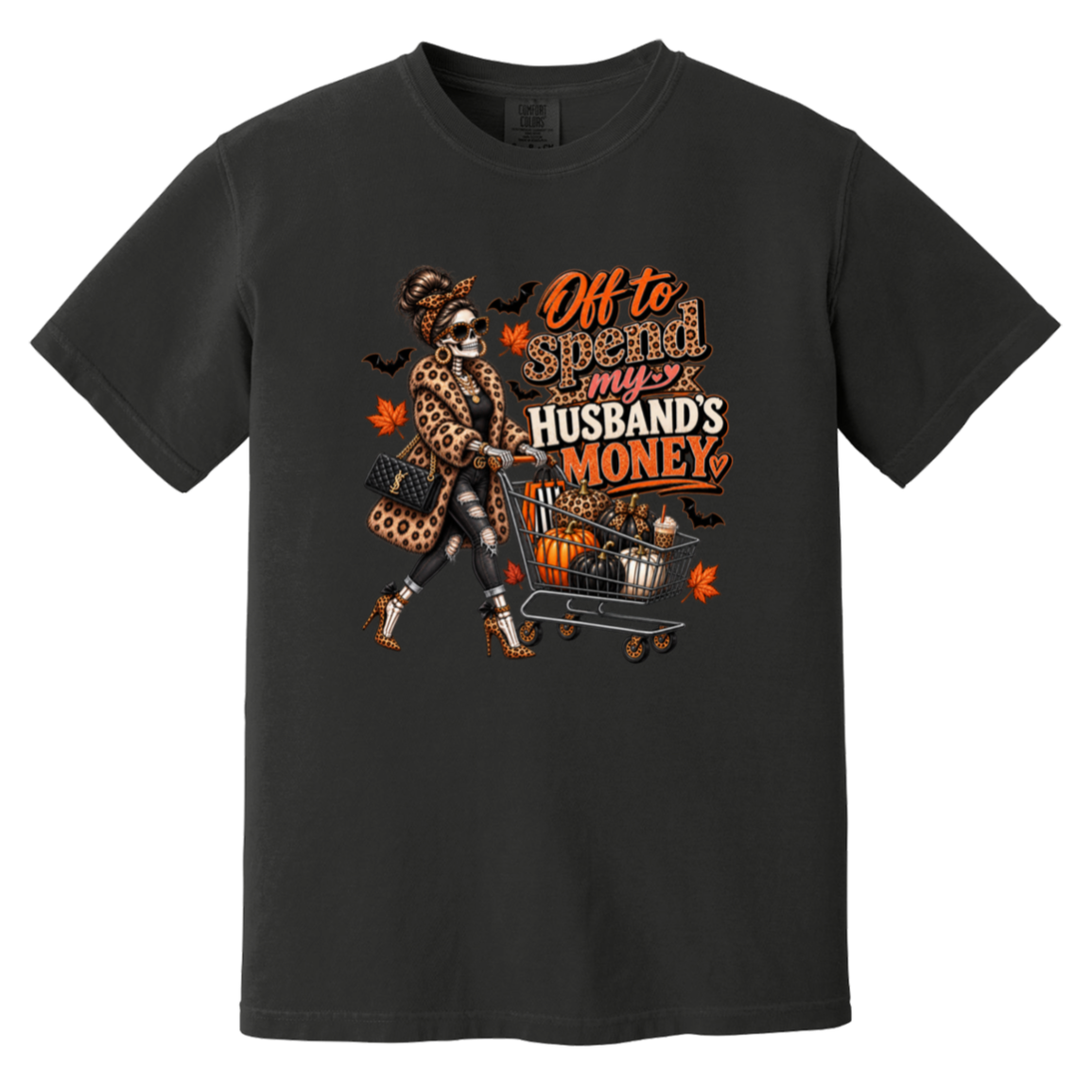 A black tshirt featuring a skeleton wearing a leopard print fur coat, pushing a shopping cart full of pumpkins with the text ‘off to spend my husbands money’ 