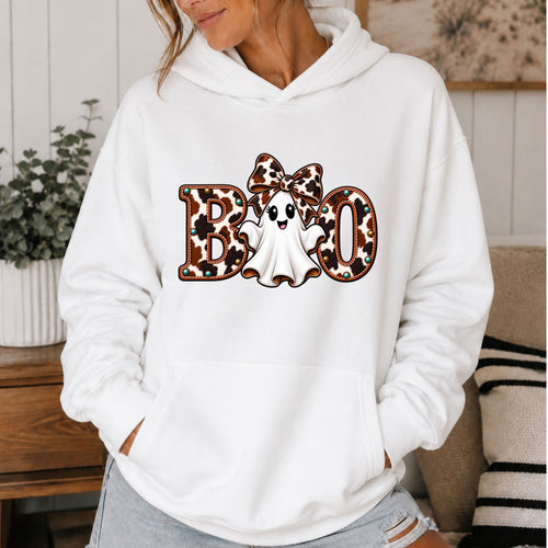 White hoodie with a ghost wearing a large cowhide bow and the word boo with the ghost in the middle of the word