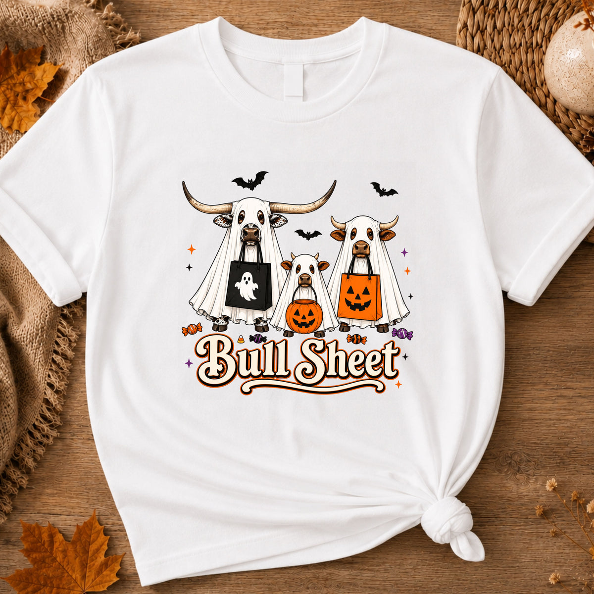 white graphic t-shirt with a cartoon design of three cows dressed in Halloween costumes and the text 'Bull Sheet'.