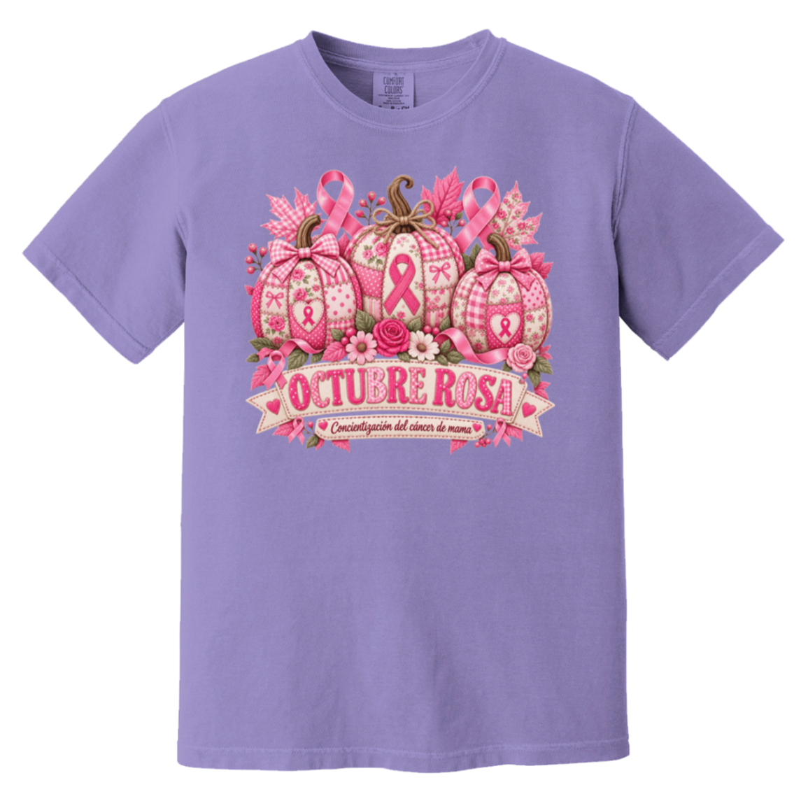 Lavender short-sleeve graphic T-shirt laid flat on a rustic wood surface with autumn leaves and woven textiles around it. The shirt features a large pink breast-cancer awareness design with three patterned pumpkins, pink ribbons, flowers, and a banner reading 'OCTUBRE ROSA' with smaller Spanish text saying “concientizacion del cancer de mama”