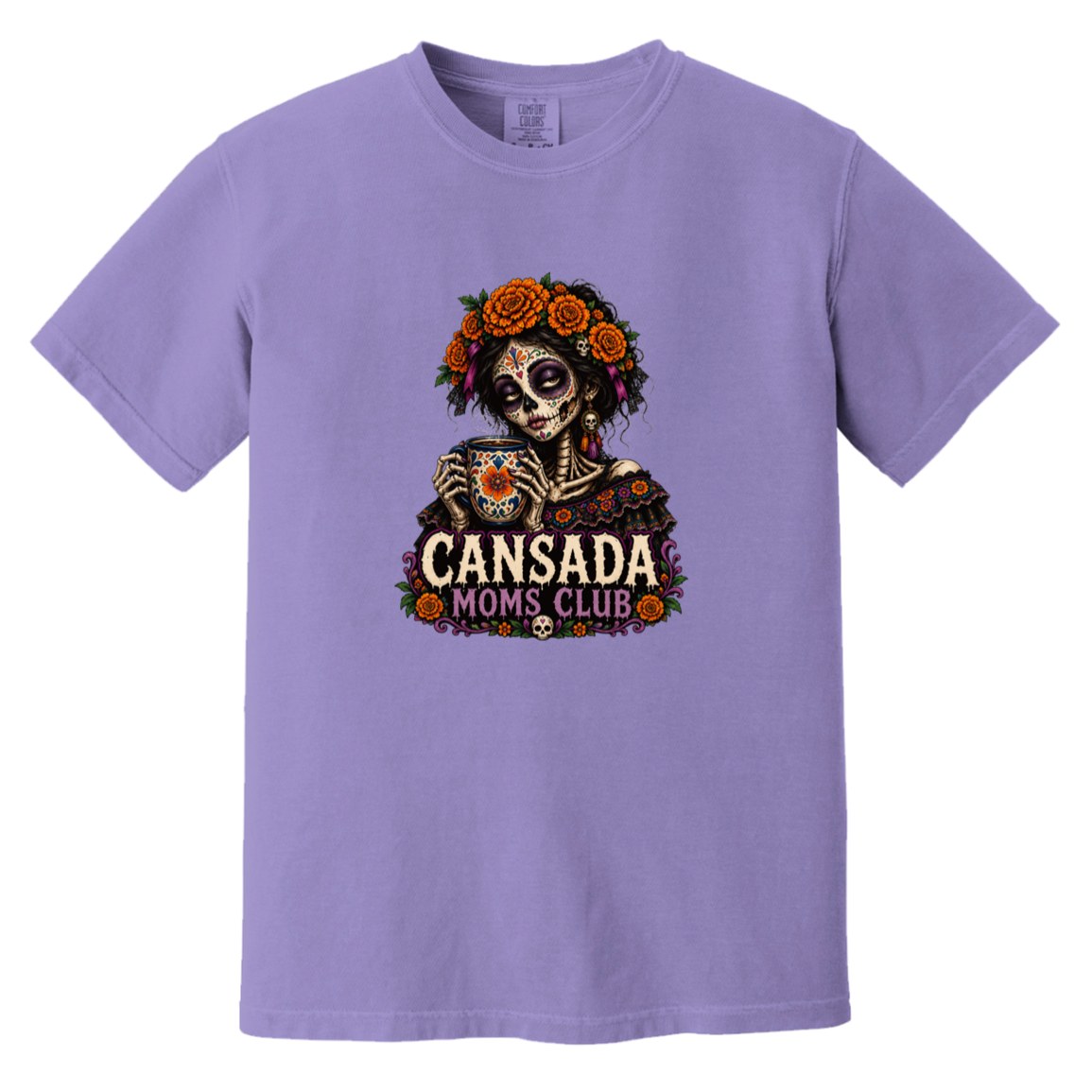 A lavender purple short-sleeve crewneck t-shirt featuring a Day of the Dead sugar skull graphic holding a teacup, surrounded by orange roses and the text 'CANSADA MOMS CLUB'.