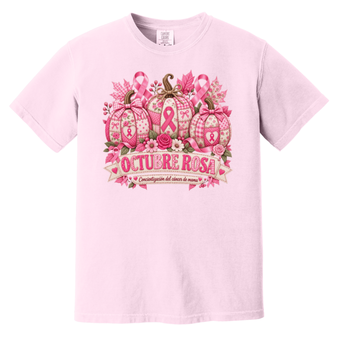 Light pink short-sleeve graphic T-shirt laid flat on a rustic wood surface with autumn leaves and woven textiles around it. The shirt features a large pink breast-cancer awareness design with three patterned pumpkins, pink ribbons, flowers, and a banner reading 'OCTUBRE ROSA' with smaller Spanish text saying “concientizacion del cancer de mama”