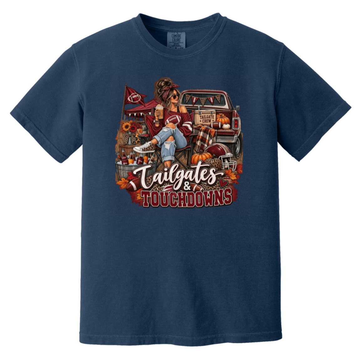 Navy blue graphic T-shirt with a detailed autumn football scene printed on the front, including a truck, pumpkins, sunflowers, and the text 'Tailgates & Touchdowns'.