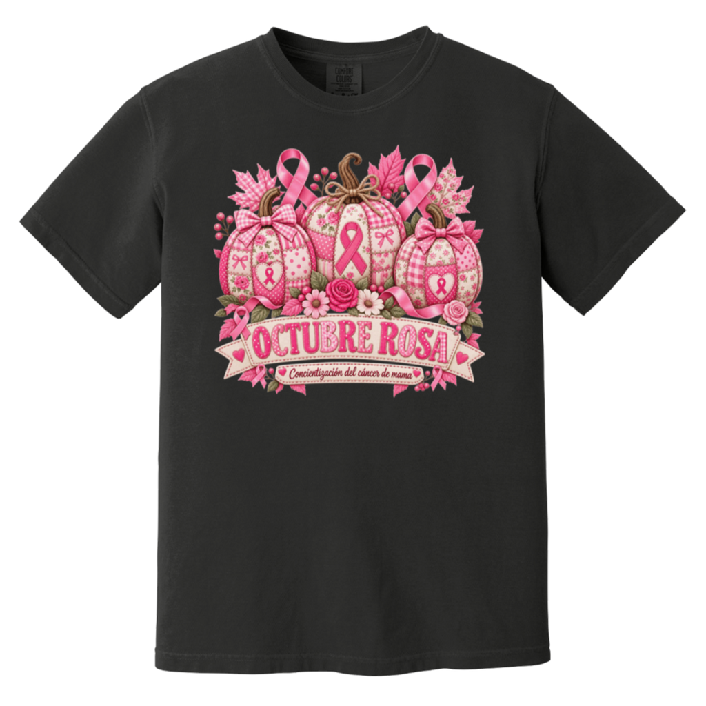 Black short-sleeve graphic T-shirt laid flat on a rustic wood surface with autumn leaves and woven textiles around it. The shirt features a large pink breast-cancer awareness design with three patterned pumpkins, pink ribbons, flowers, and a banner reading 'OCTUBRE ROSA' with smaller Spanish text saying “concientizacion del cancer de mama”