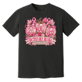 Black short-sleeve graphic T-shirt laid flat on a rustic wood surface with autumn leaves and woven textiles around it. The shirt features a large pink breast-cancer awareness design with three patterned pumpkins, pink ribbons, flowers, and a banner reading 'OCTUBRE ROSA' with smaller Spanish text saying “concientizacion del cancer de mama”