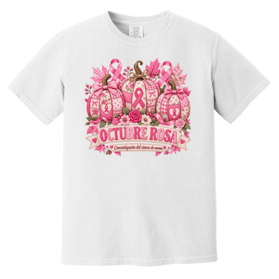 White short-sleeve graphic T-shirt laid flat on a rustic wood surface with autumn leaves and woven textiles around it. The shirt features a large pink breast-cancer awareness design with three patterned pumpkins, pink ribbons, flowers, and a banner reading 'OCTUBRE ROSA' with smaller Spanish text saying “concientizacion del cancer de mama”