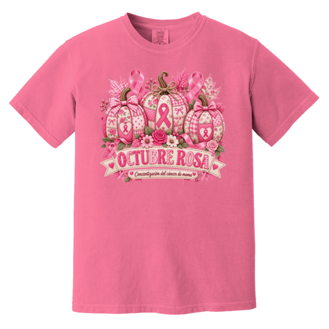 Pink short-sleeve graphic T-shirt laid flat on a rustic wood surface with autumn leaves and woven textiles around it. The shirt features a large pink breast-cancer awareness design with three patterned pumpkins, pink ribbons, flowers, and a banner reading 'OCTUBRE ROSA' with smaller Spanish text saying “concientizacion del cancer de mama”
