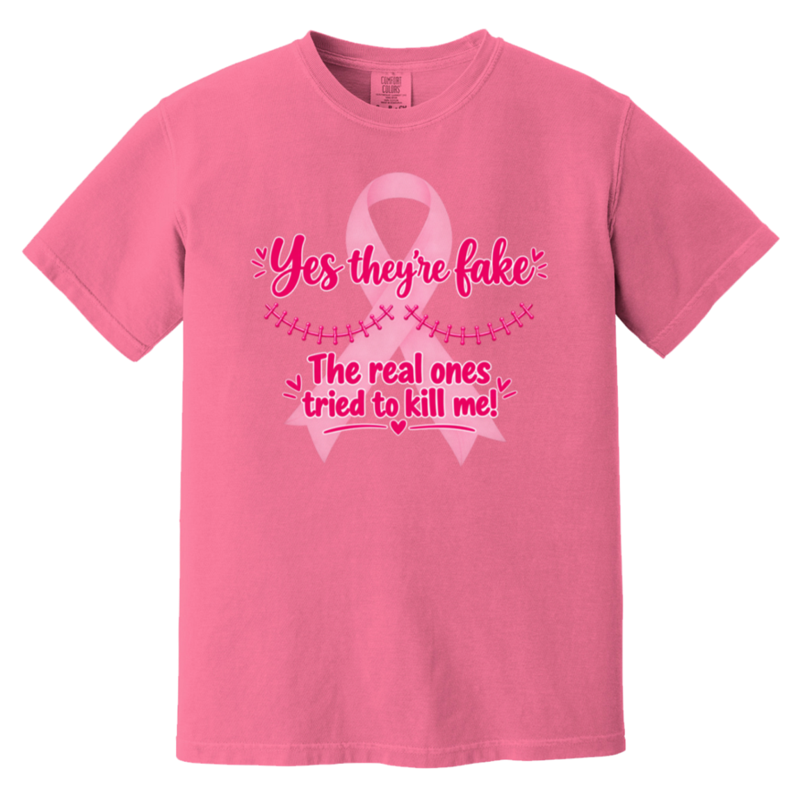 Pink short-sleeve t-shirt with a pink graphic on the front. The graphic features a pink ribbon and the text 'Yes they're fake' and 'The real ones tried to kill me!' in pink lettering.