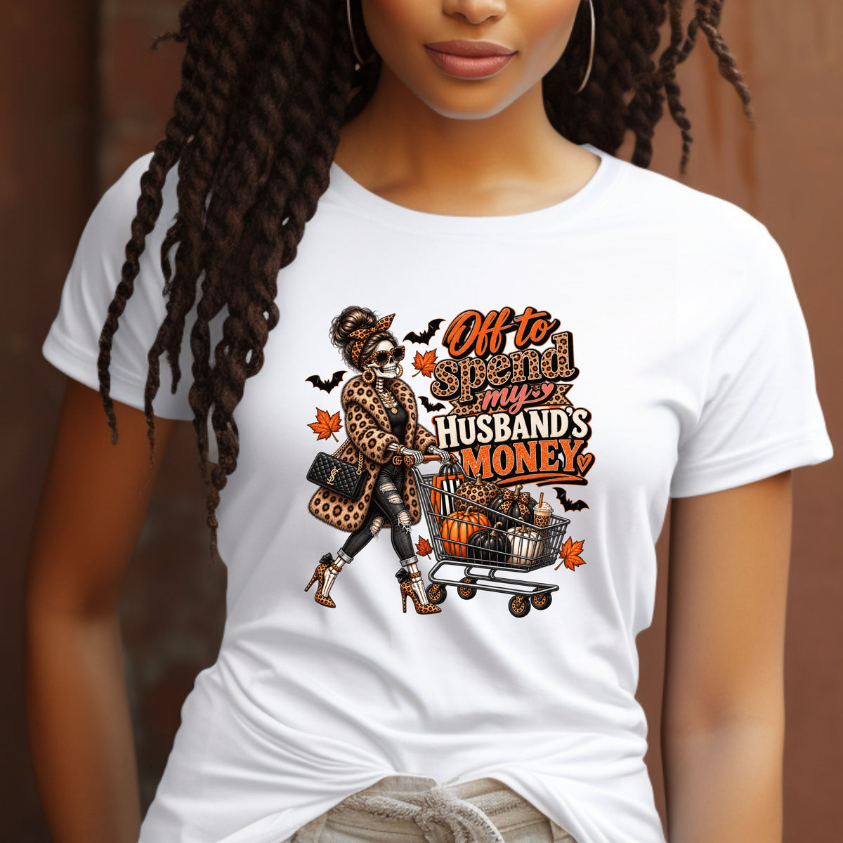 A white tshirt featuring a skeleton wearing a leopard print fur coat, pushing a shopping cart full of pumpkins with the text ‘off to spend my husbands money’ 