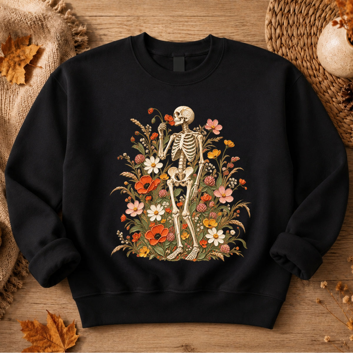 A black crewneck sweatshirt featuring a vintage-style graphic of a skeleton standing amidst a colorful field of wildflowers. 