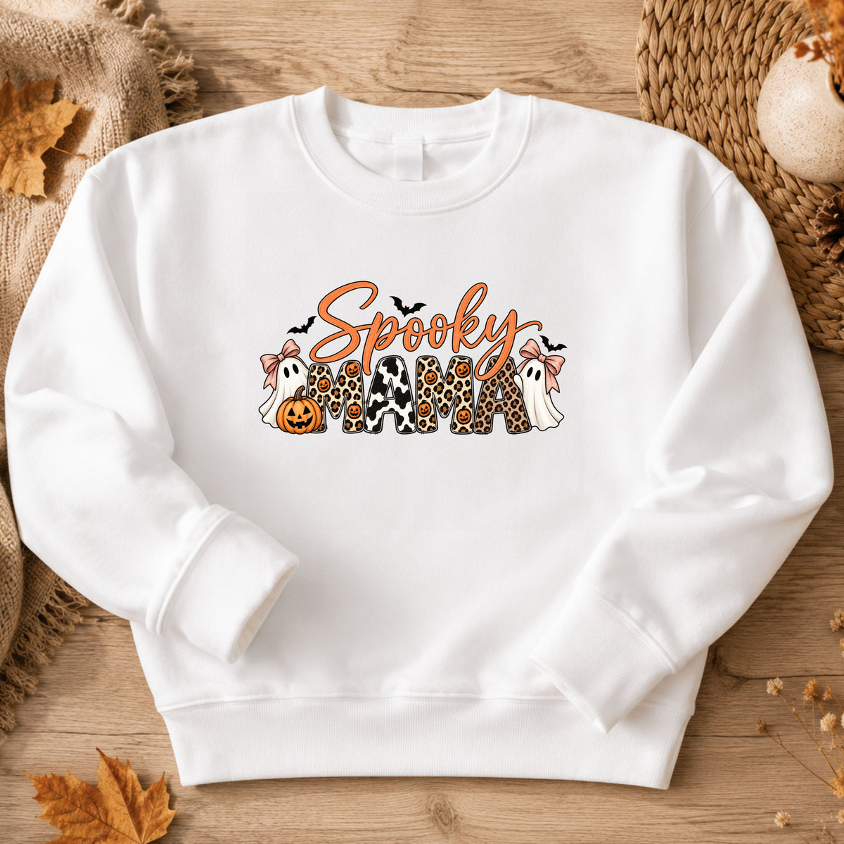 white crewneck sweatshirt with a 'Spooky Mama' graphic featuring Halloween-themed characters and patterns.