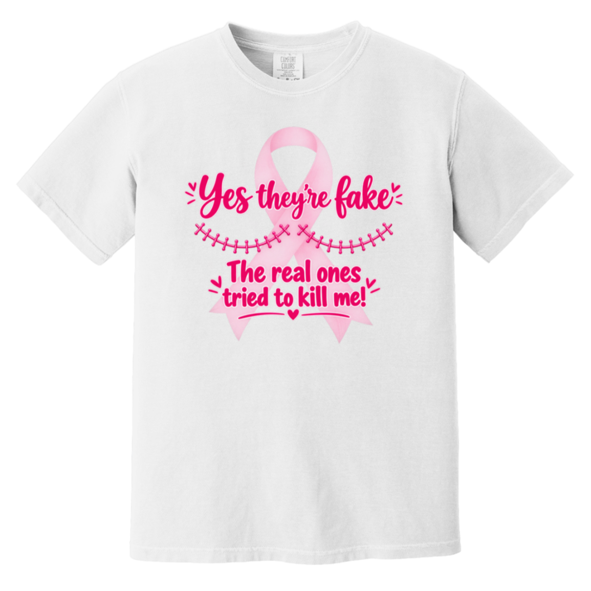 White short-sleeve t-shirt with a pink graphic on the front. The graphic features a pink ribbon and the text 'Yes they're fake' and 'The real ones tried to kill me!' in pink lettering.