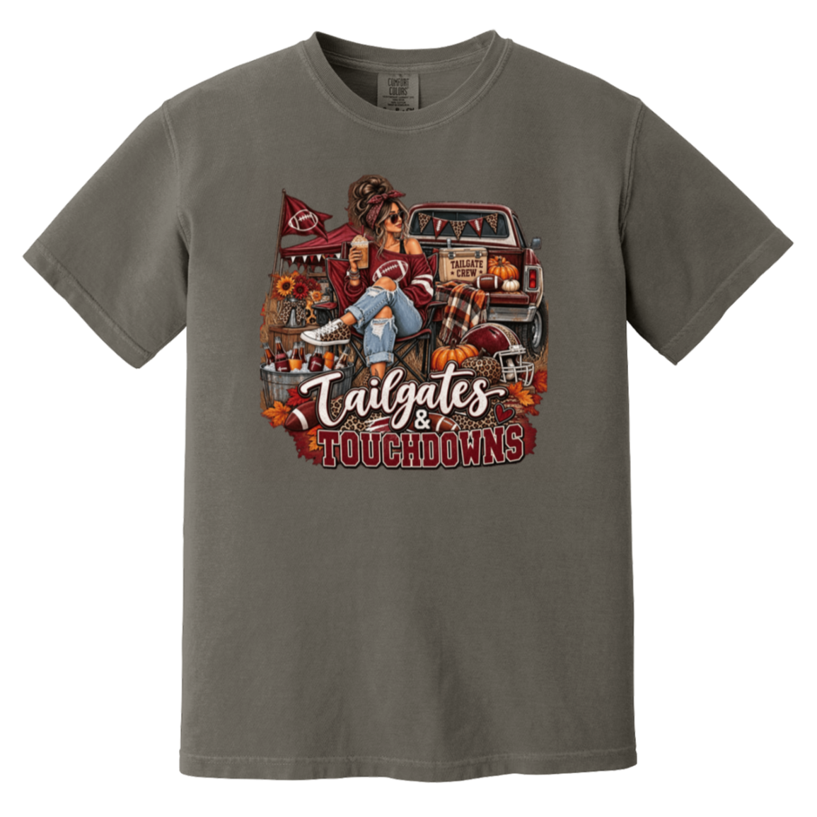 Dark gray graphic T-shirt with a detailed autumn football scene printed on the front, including a truck, pumpkins, sunflowers, and the text 'Tailgates & Touchdowns'.