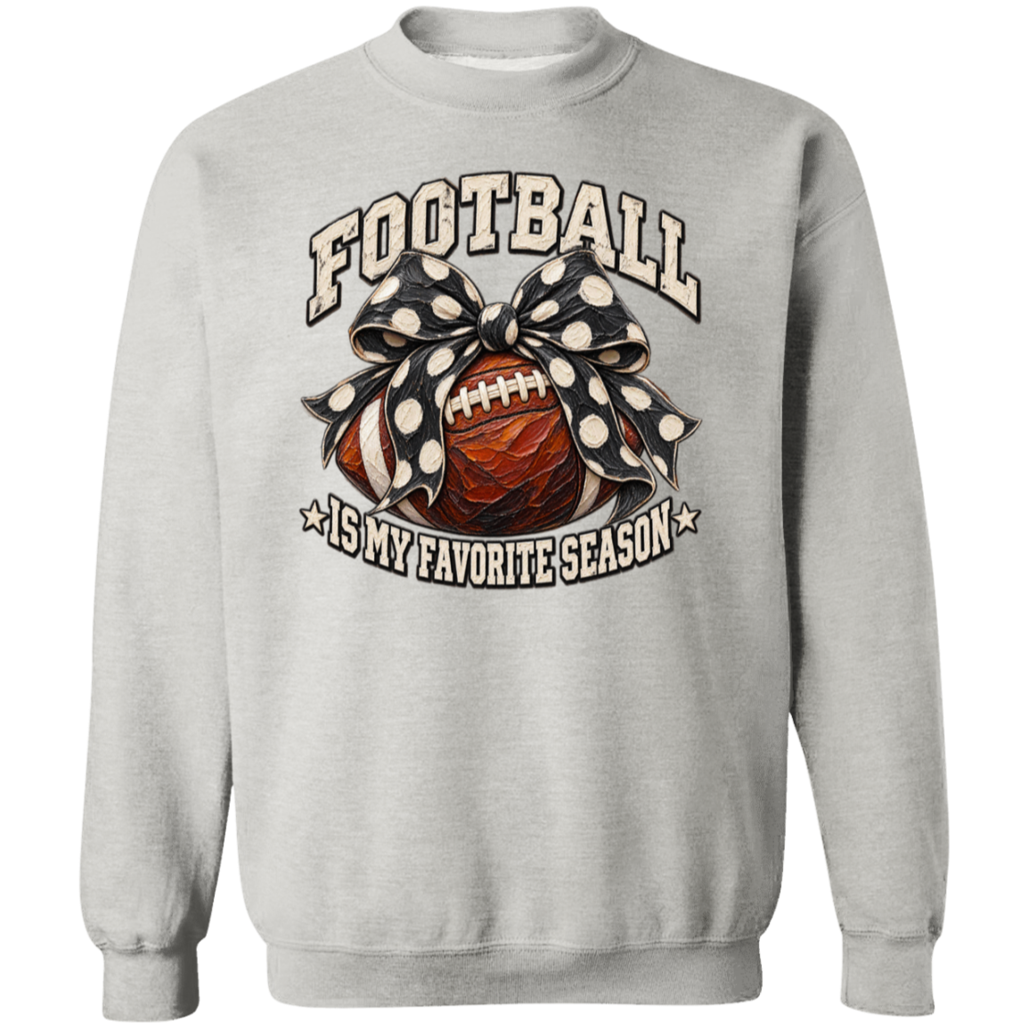 A light gray crewneck sweatshirt featuring a graphic design on the front with the text 'FOOTBALL IS MY FAVORITE SEASON'. The graphic depicts a brown football wrapped in a black and white polka dot bow, set against a clean white background.