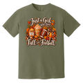 An olive green short-sleeve t-shirt with a 'Just a Girl Who Loves Fall and Football' graphic on the front, featuring autumn leaves, pumpkins, a football, and a jar of pumpkin spice latte.