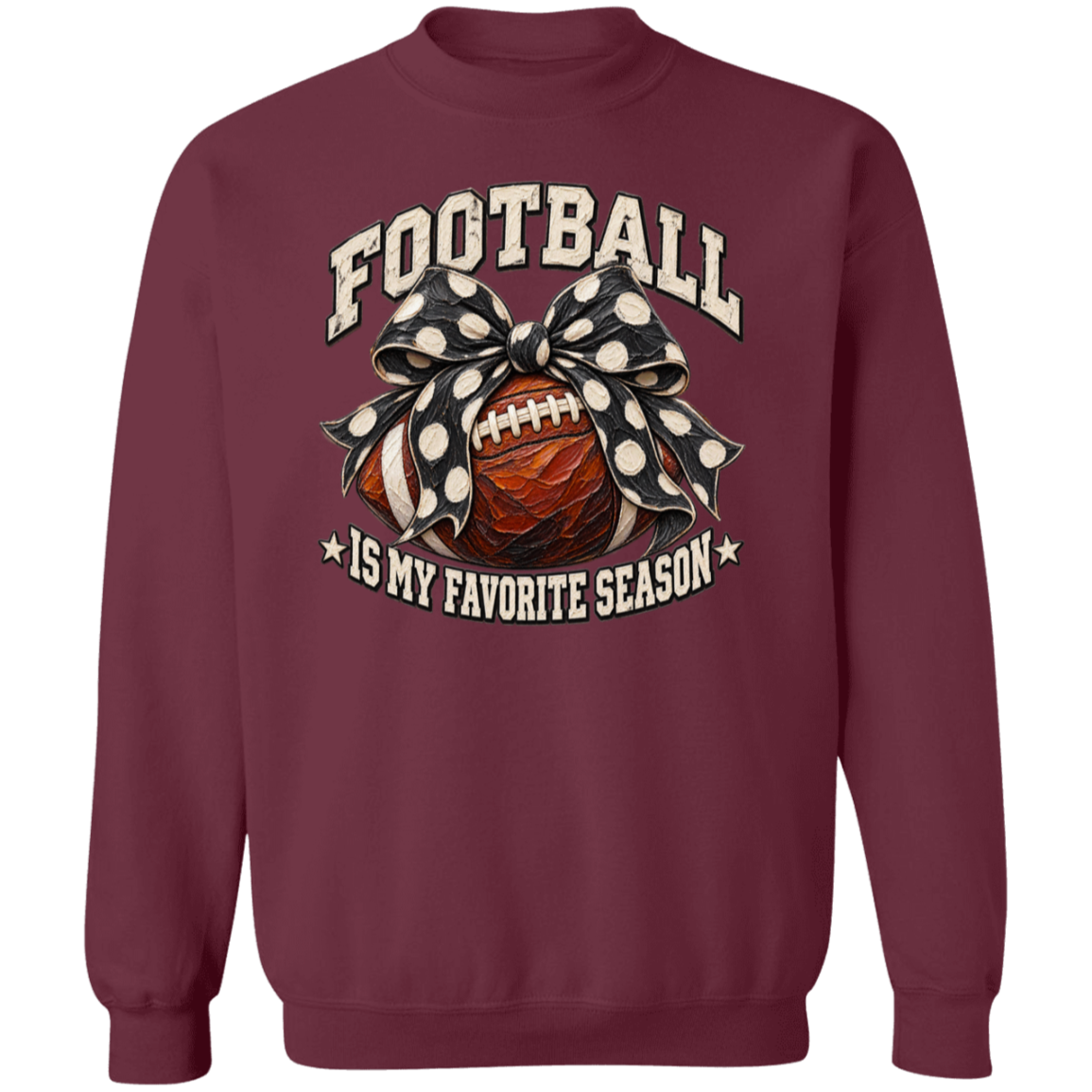 A maroon crewneck sweatshirt featuring a graphic design on the front with a football, a black-and-white polka dot bow, and the text 'FOOTBALL IS MY FAVORITE SEASON' in cream and white.