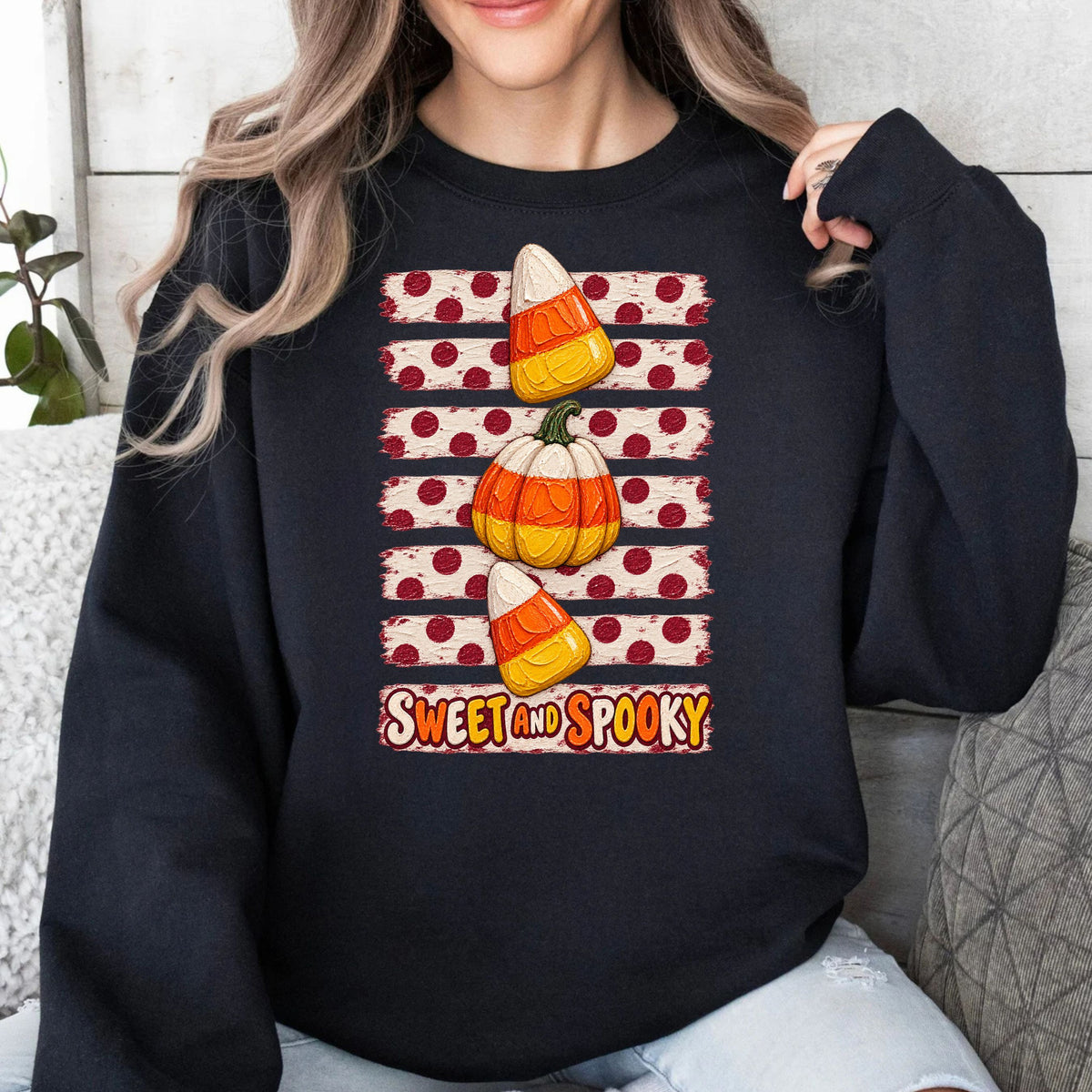 a black sweatshirt with candy corn snd pumpkin graphics with horizontal white and burgundy polkadot lines 