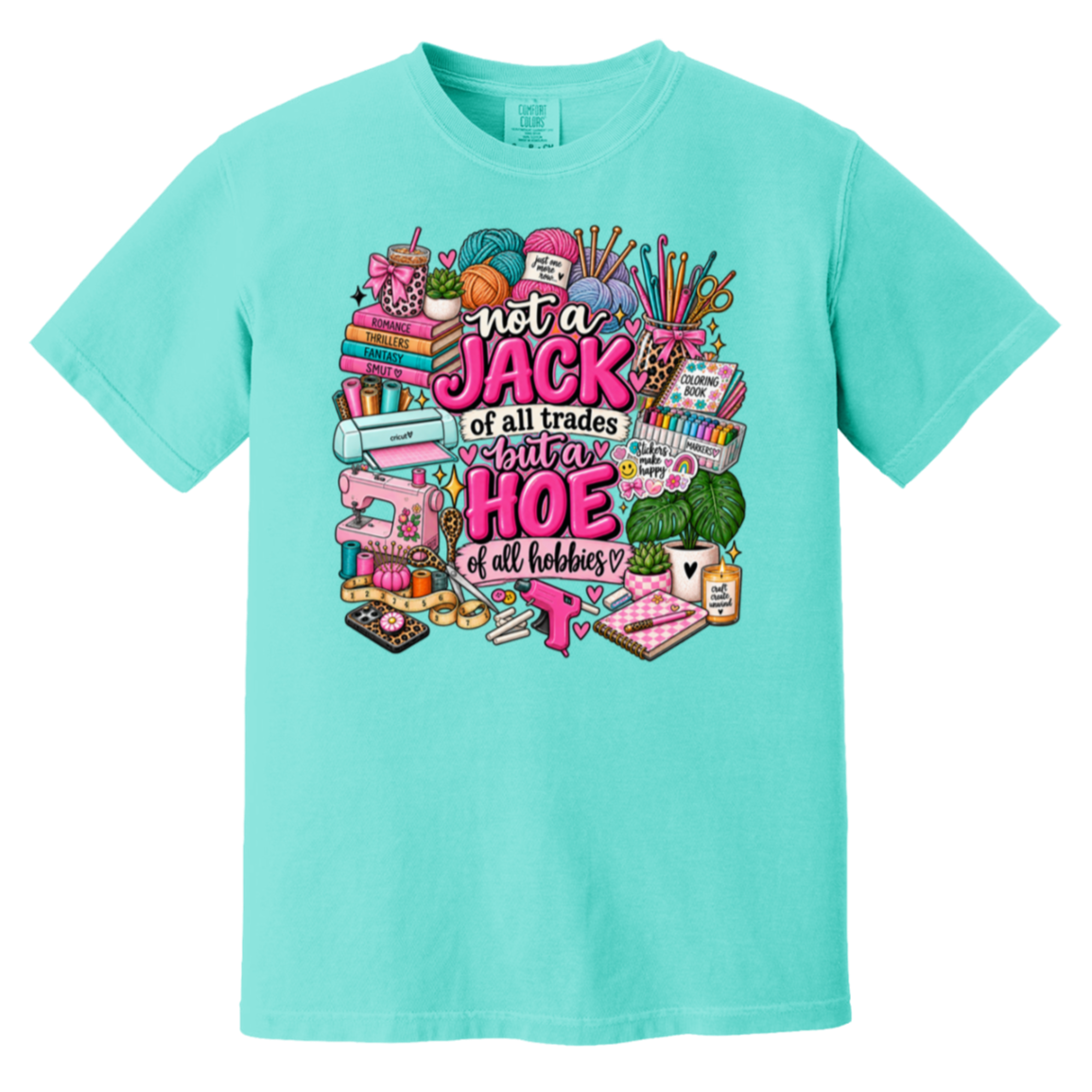 A turquoise short-sleeve crewneck t-shirt featuring a colorful graphic print on the front. The graphic contains various sewing and crafting tools (spools of thread, a sewing machine, scissors, fabric) surrounding the text 'not a JACK of all trades but a HOE of all hobbies' in pink and white lettering.