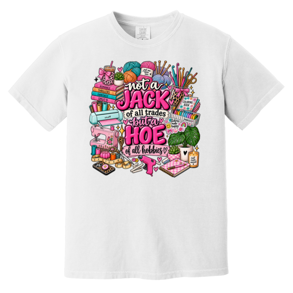A white short-sleeve crewneck t-shirt featuring a colorful graphic print on the front. The graphic contains various hand-drawn sewing and crafting tools (spools of yarn, a sewing machine, scissors, fabric) and the text 'not a JACK of all trades but a HOE of all hobbies' in pink and black lettering.